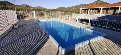 Прямоугольный бассейн с ограждением и растительностью вокруг