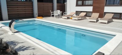 Прямоугольный композитный бассейн с водопадом и шезлонгами во внутреннем дворе